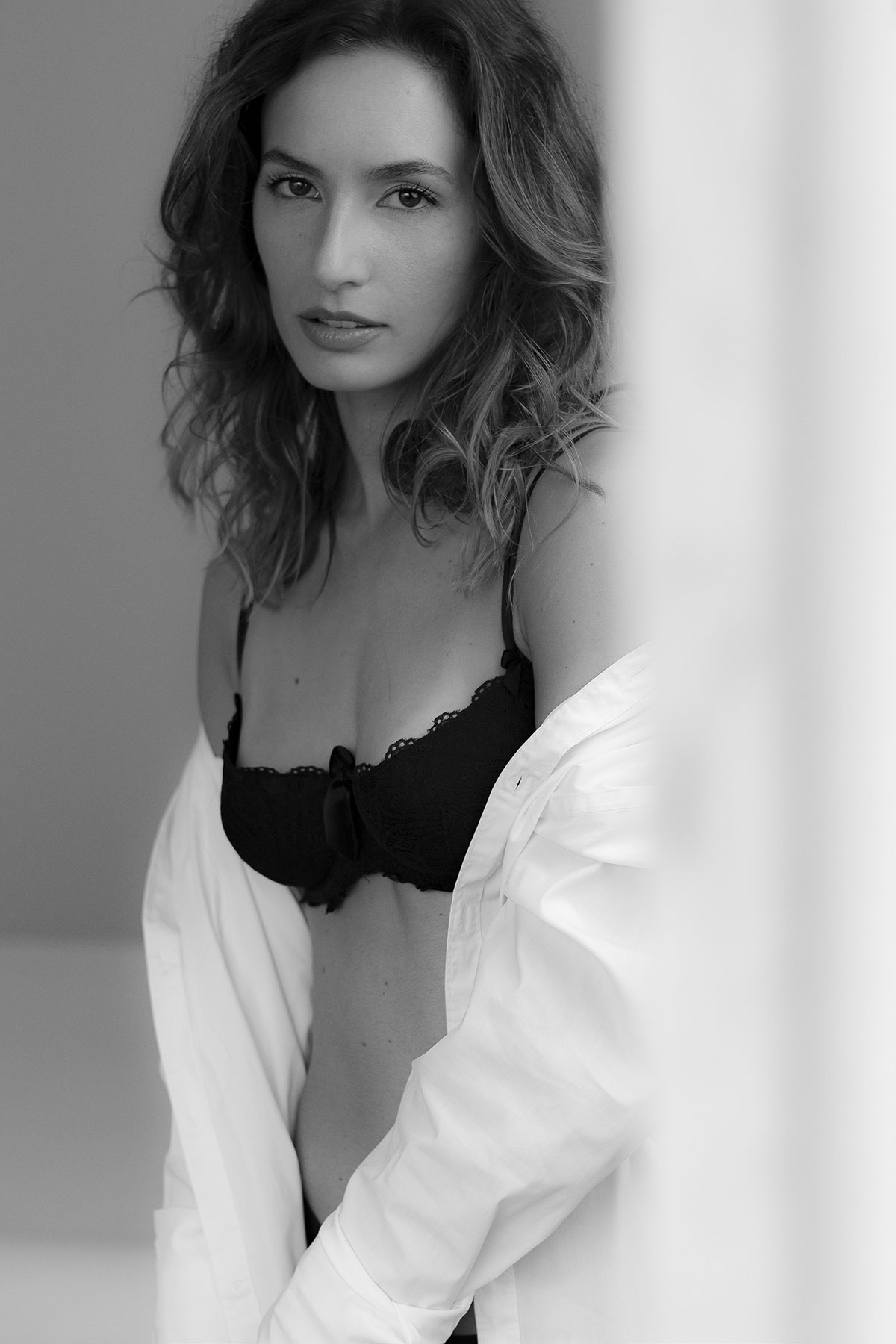 Retrato boudoir feminino em estúdio, com lingerie preta e camisa branca, fotografado por Danniela Senra em Castelo Branco
