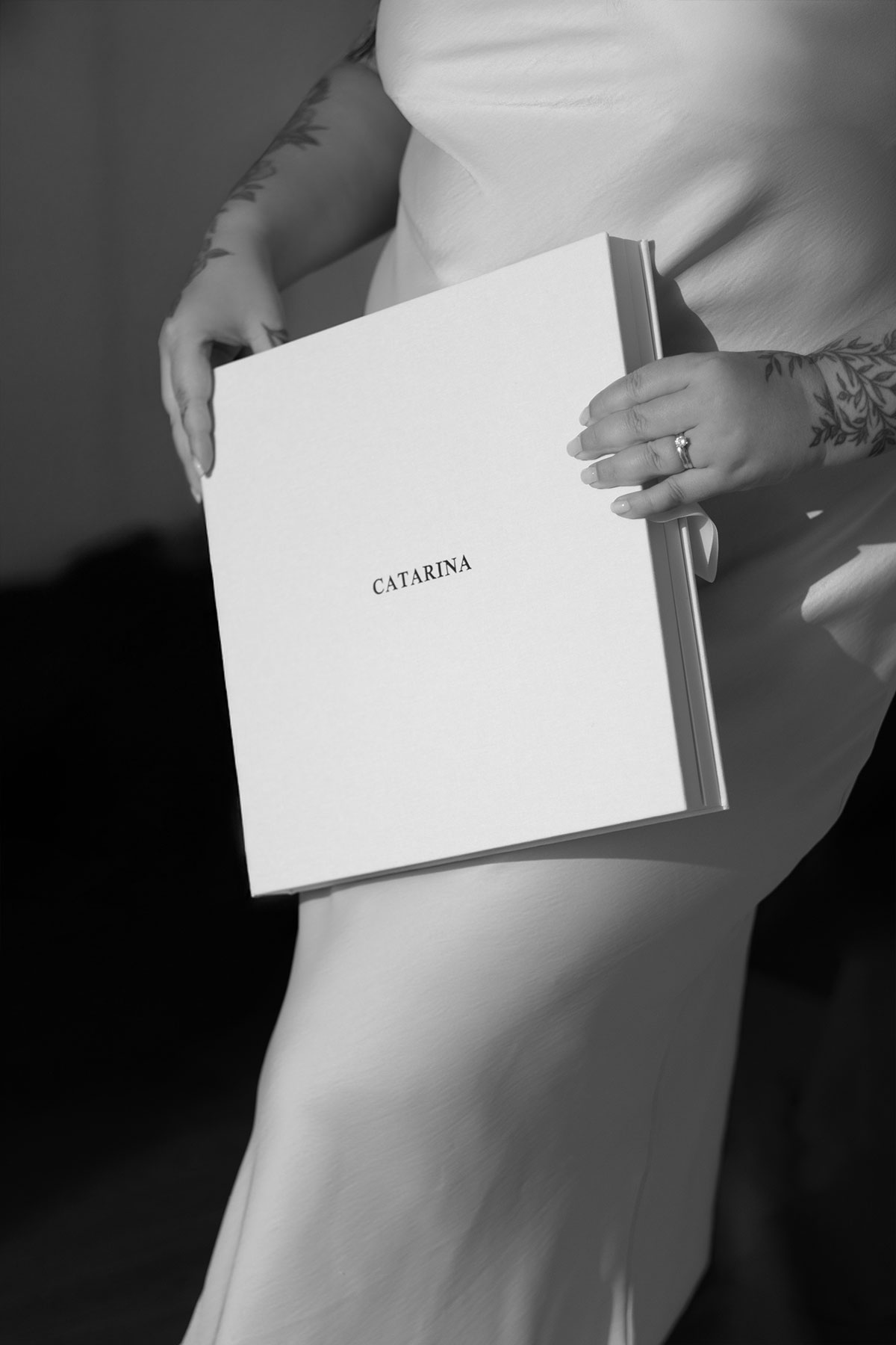 detalhes em preto e branco da fotografa a segurar a caixa personalizada com o nome gravado