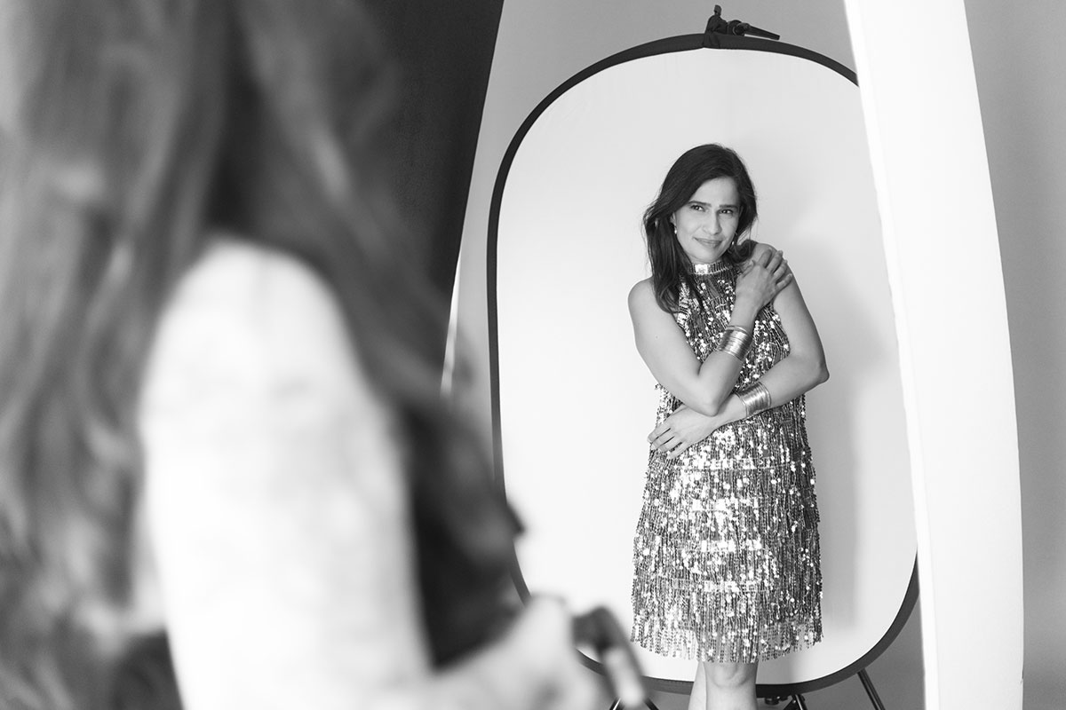 bastidores da fotografa mostrando a pose a cliente que esta com um vestido de lantejoulas