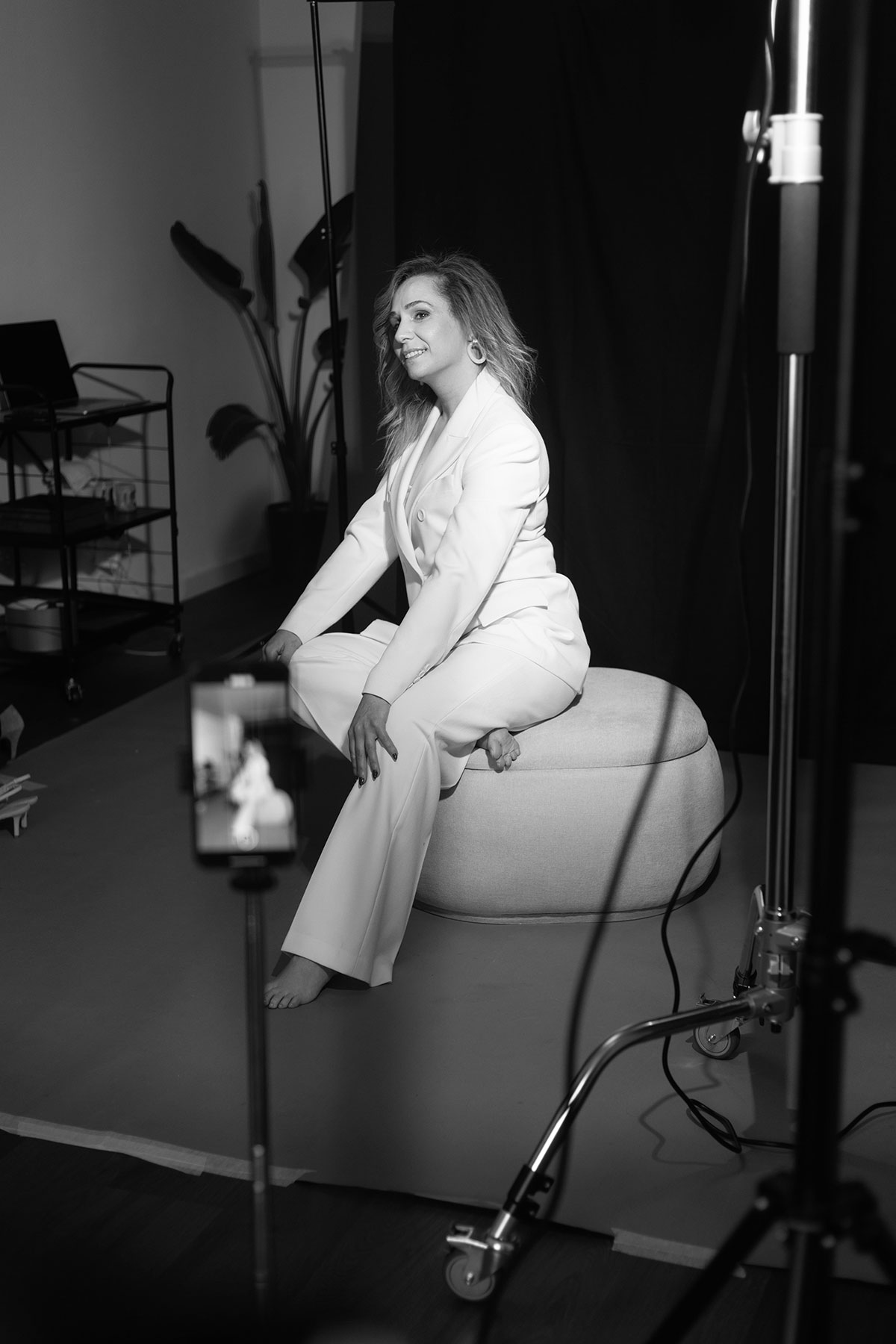 Modelo a posar em estúdio fotográfico, vestida com fato branco e descalça.