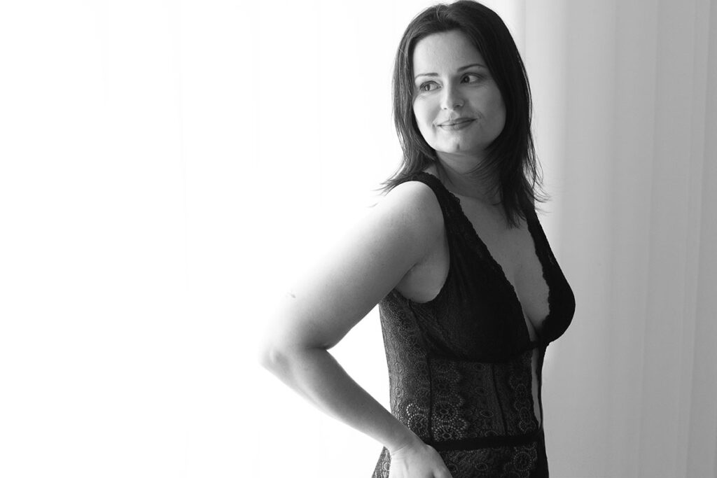 retrato intimista, preto e branco, mulher a olhar para o lado e com um body escuro rendado e decotado