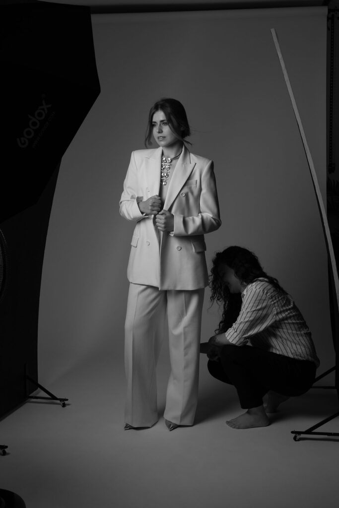 bastidores em preto e branco com uma mulher de fato bege