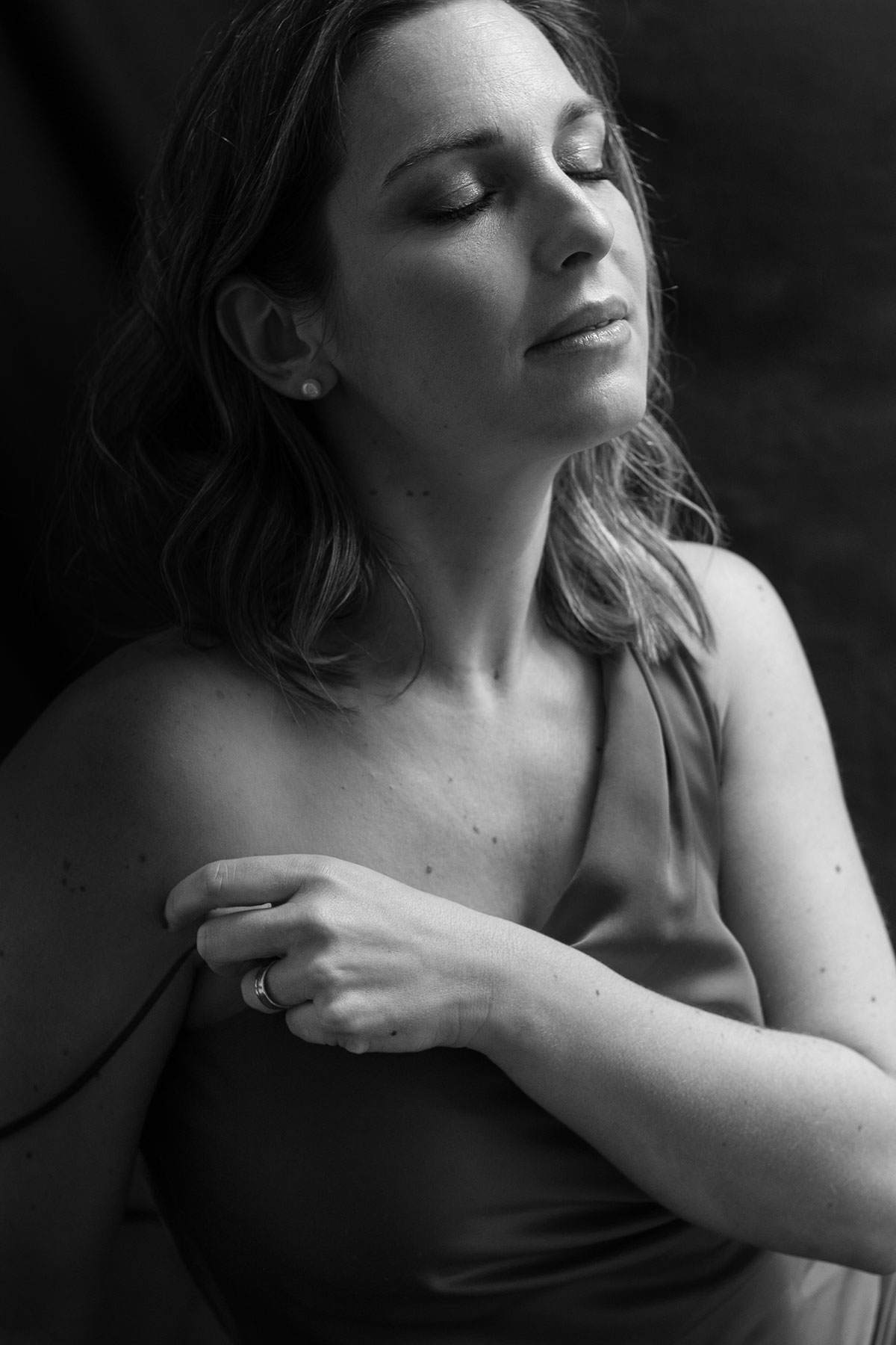 Retrato feminino intimista em estúdio, mulher de olhos fechados em preto e branco com expressão serena