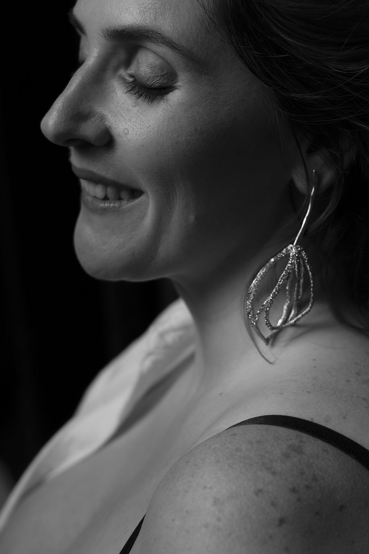 Retrato feminino close-up em estúdio, mulher sorridente em preto e branco com brinco elegante