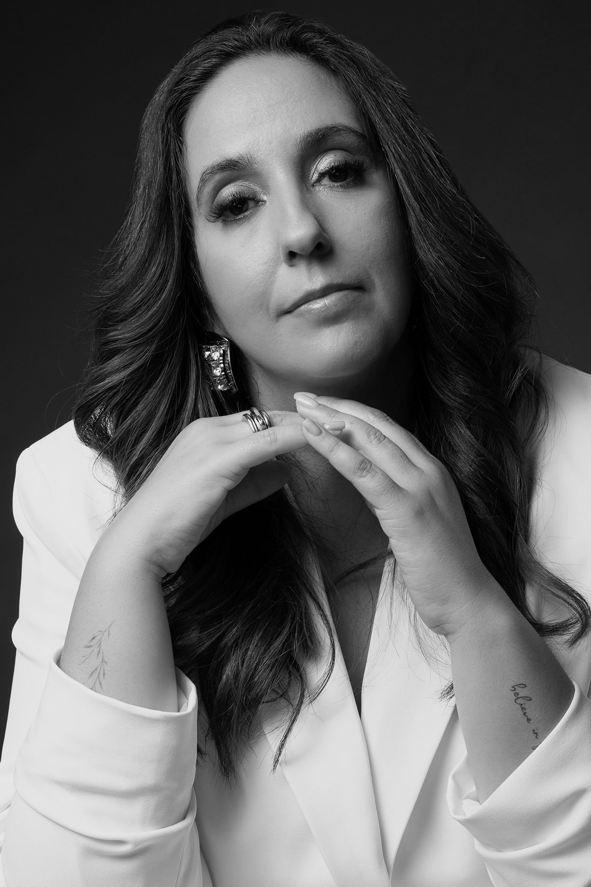 Retrato feminino em estúdio, em preto e branco, com expressão confiante e fato branco