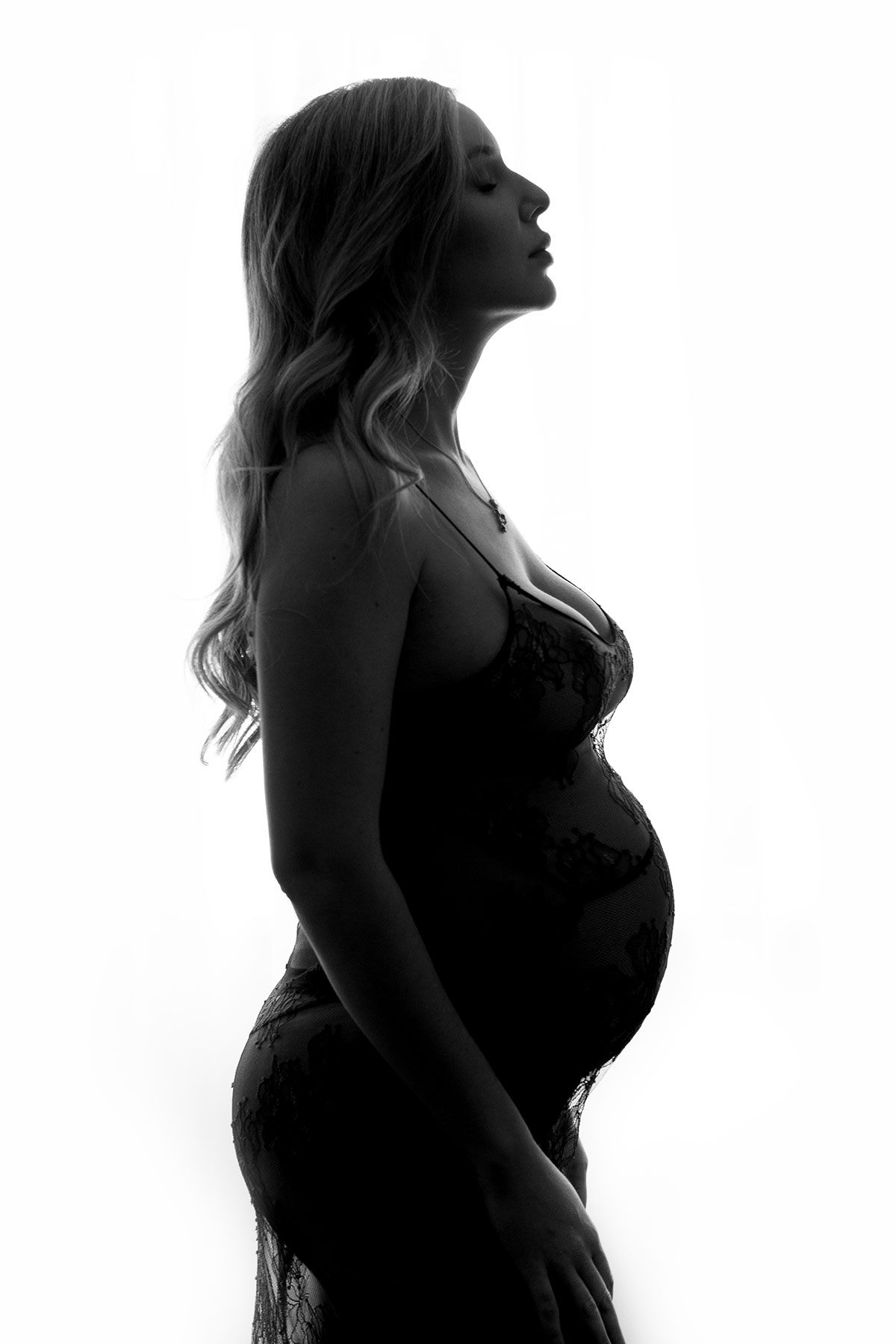silhueta de mulher grávida em sessão fotográfica de estúdio iluminação de contraluz